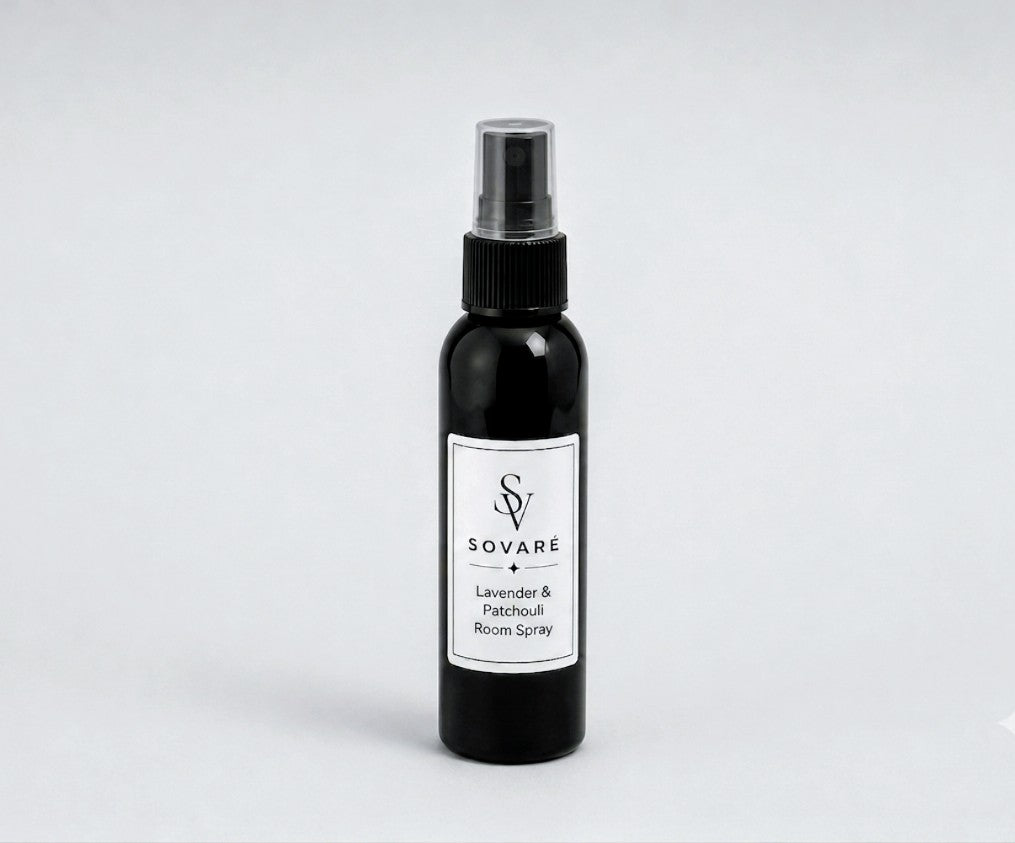 Rows of dark black room spray bottles with white labels arranged on a concrete floor.